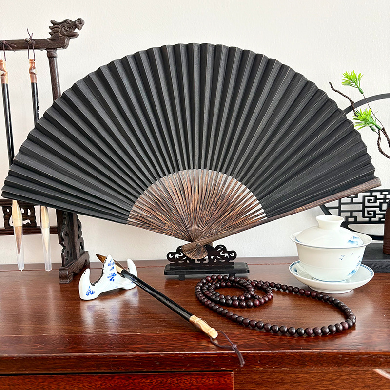 Intangible Heritage Handcrafted Black Paper Folding Fan fully open on scholar's desk